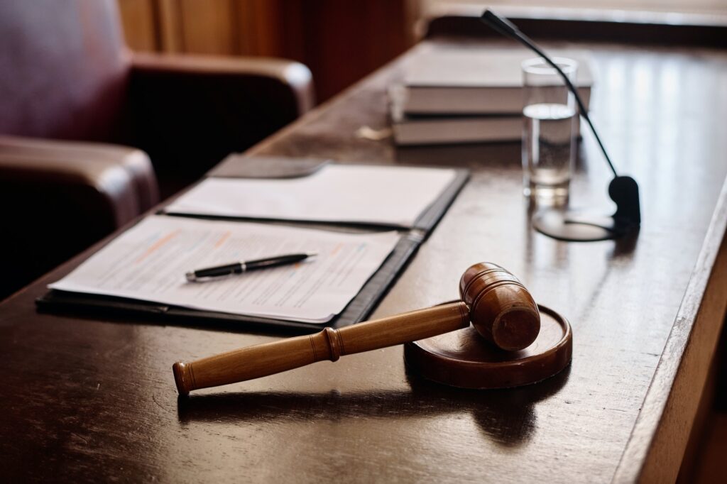 Wooden gavel on sounding block fixed on desk of judge with juridical documents